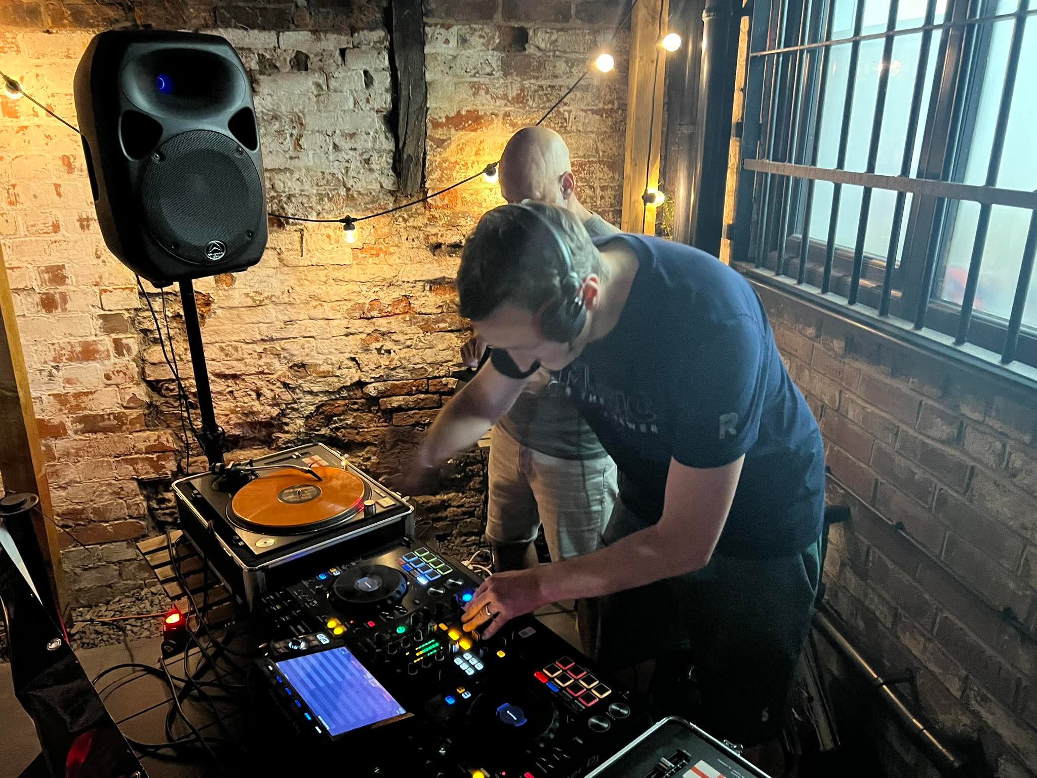 Nick Hopewell DJing in a stone-walled venue