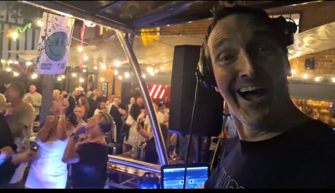 Nick Hopewell with a lively crowd behind the DJ booth