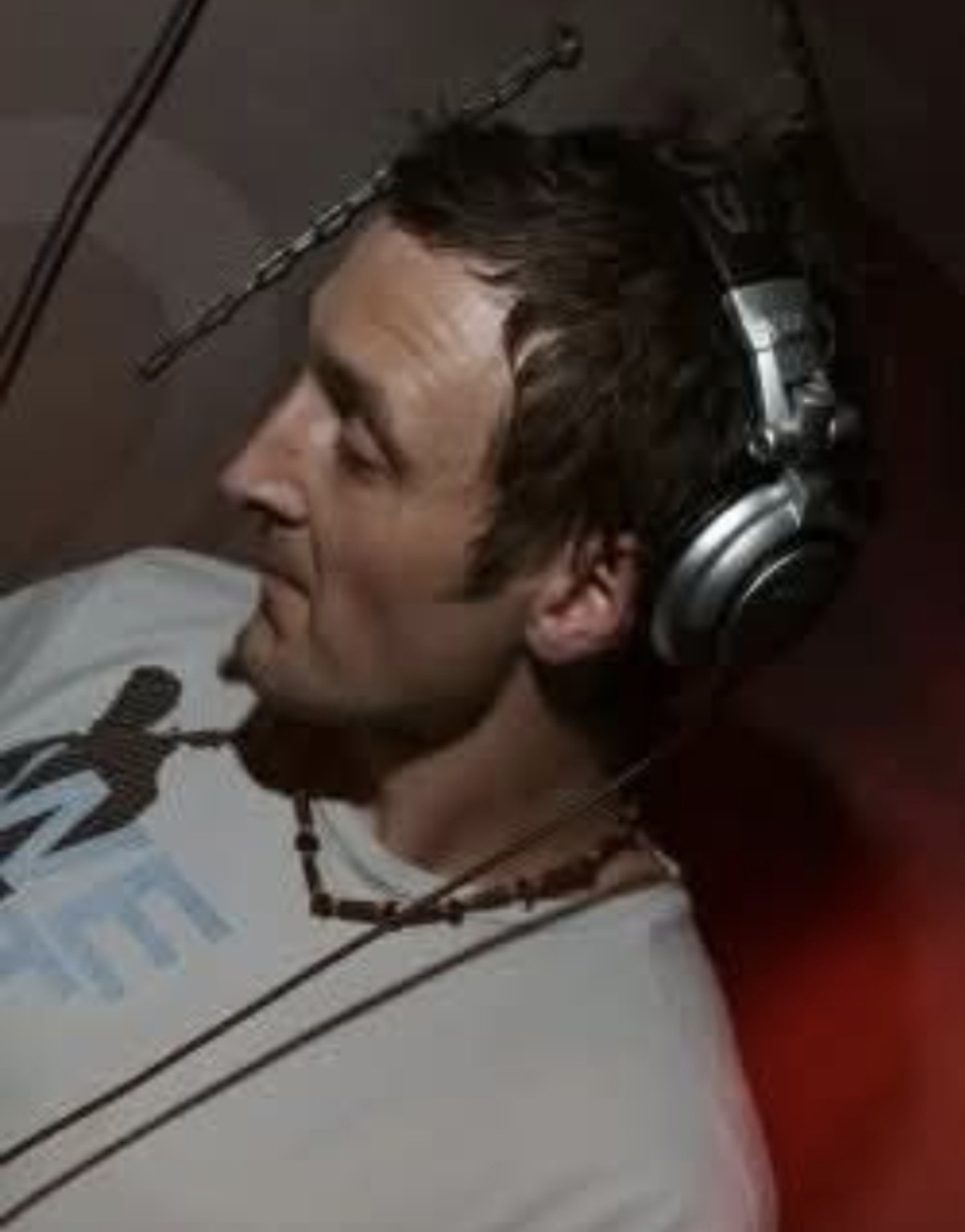Side-profile photograph of Nick Hopewell DJing in a grey T-shirt and headphones